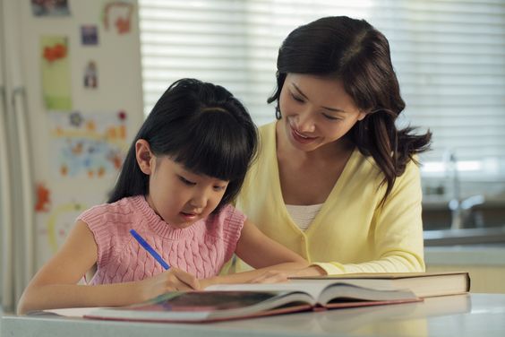 A mother helps her daughter with homework.